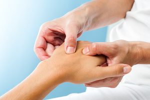 Therapist doing massage on female hand.